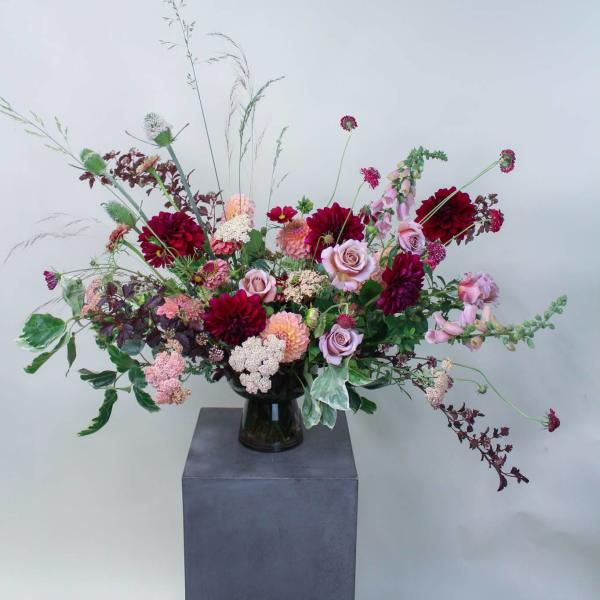 Large mixed bouquet of pink and burgundy flowers in a dark vase