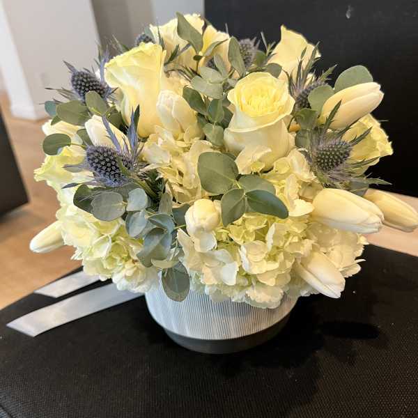 Yellow roses and white tulips arranged in a striped vase