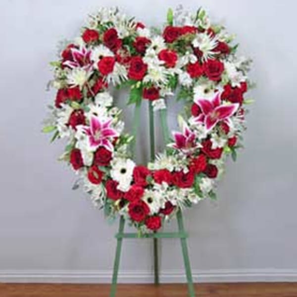 Heart-shaped floral wreath on a standing easel with red, white, and pink flowers
