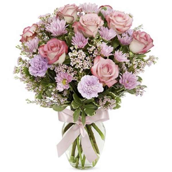Pink roses and lavender flowers in a glass vase with a pink ribbon