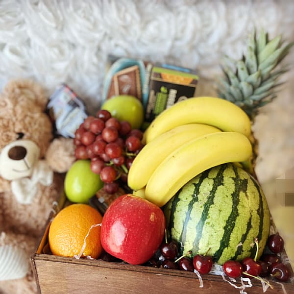 Gift basket with fruit, chocolates, and a teddy bear