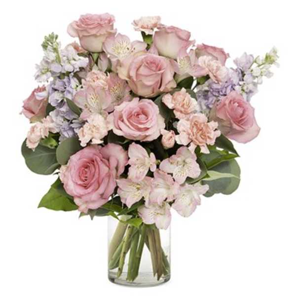Pink roses and pale flowers arranged in a clear glass vase