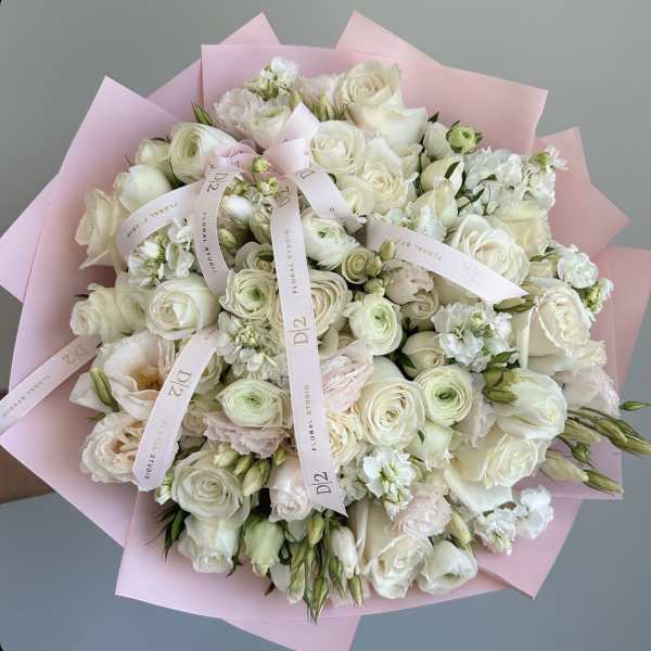 Bouquet of white roses and pale pink flowers wrapped in pink paper