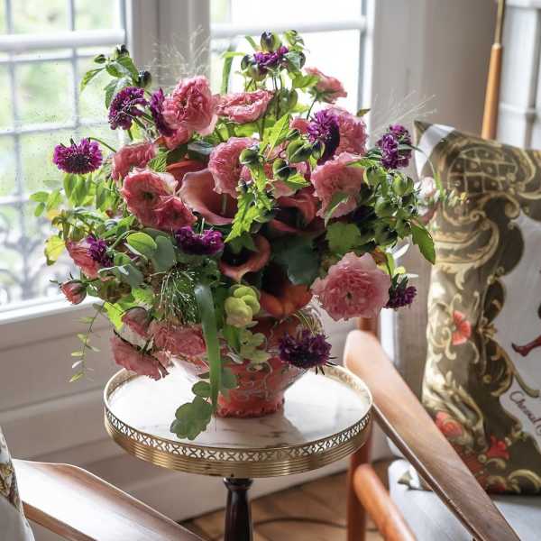 Pink and purple floral arrangement in a decorative vase on a small table