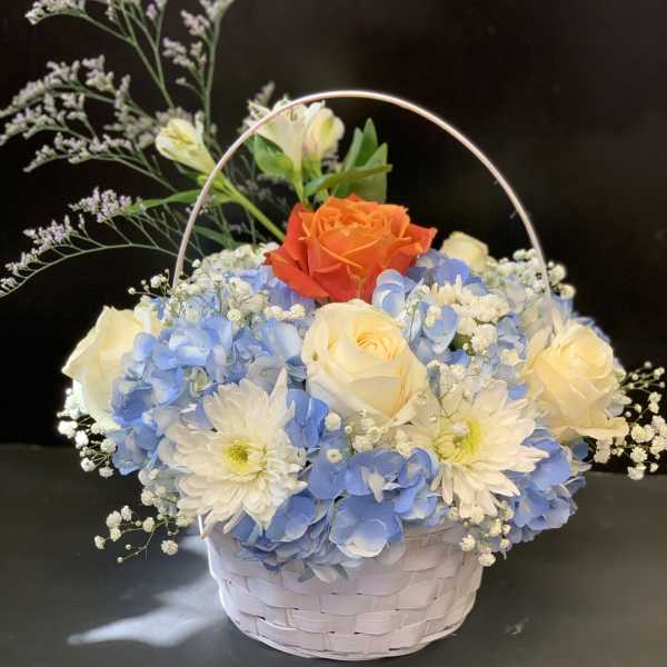 Basket of blue hydrangeas, white roses, and an orange rose