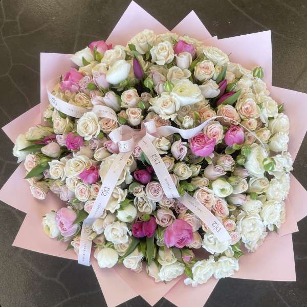 Large bouquet of pink and white roses wrapped in pale pink paper