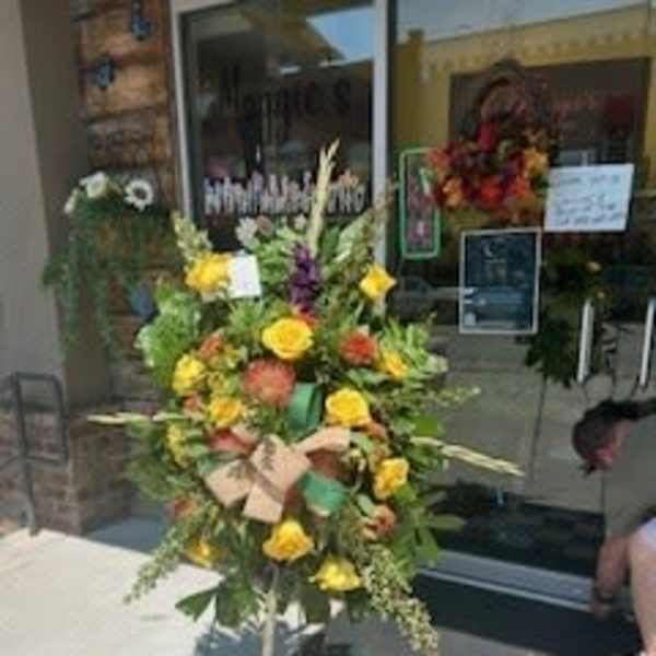 Tall floral standing spray with yellow and orange blooms on an easel