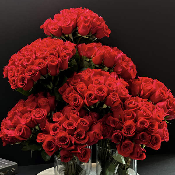 Clusters of red roses arranged in clear glass vases on a round base