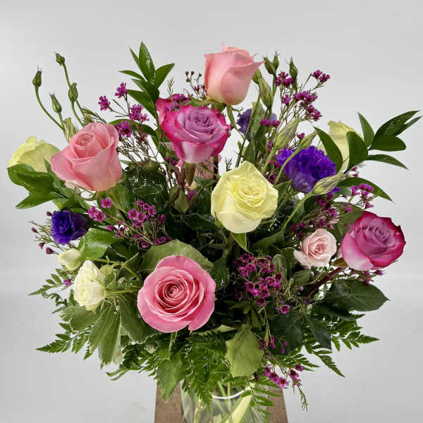 Mixed roses in a glass vase with purple filler flowers