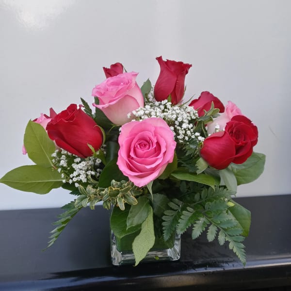 Pink and red roses arranged in a square glass vase