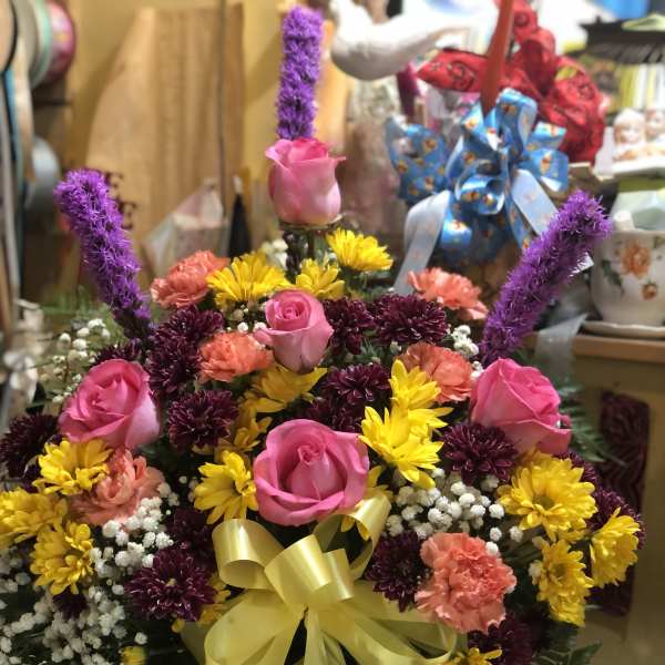 Pink roses and mixed daisies in a white vase with a yellow bow