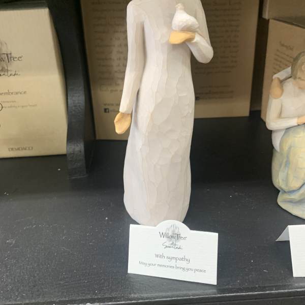 A small angel figurine in a white dress holding a dove