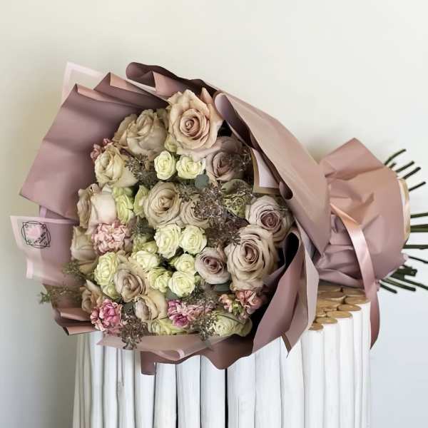 Bouquet of blush and cream roses wrapped in pink paper