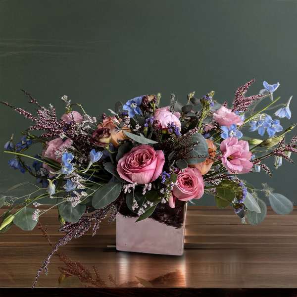 Pink roses and blue flowers in a square vase