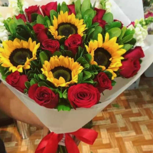 Bouquet of red roses and sunflowers wrapped in white paper