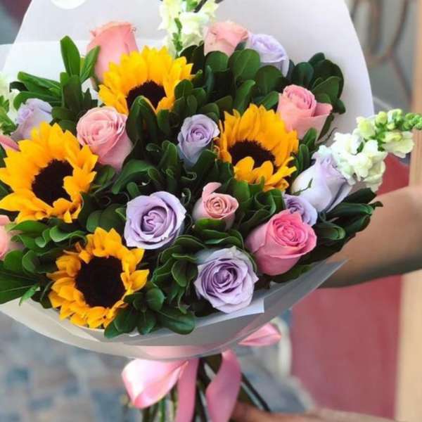 Bouquet of sunflowers and pastel roses wrapped in white paper