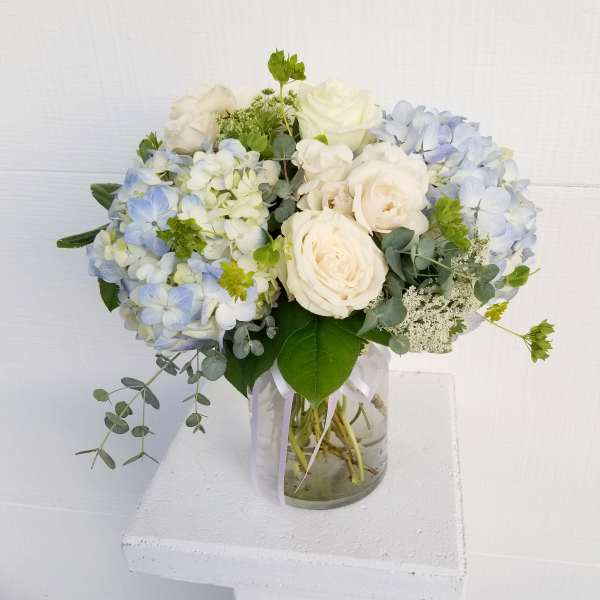 White and pale blue flower bouquet in a glass vase