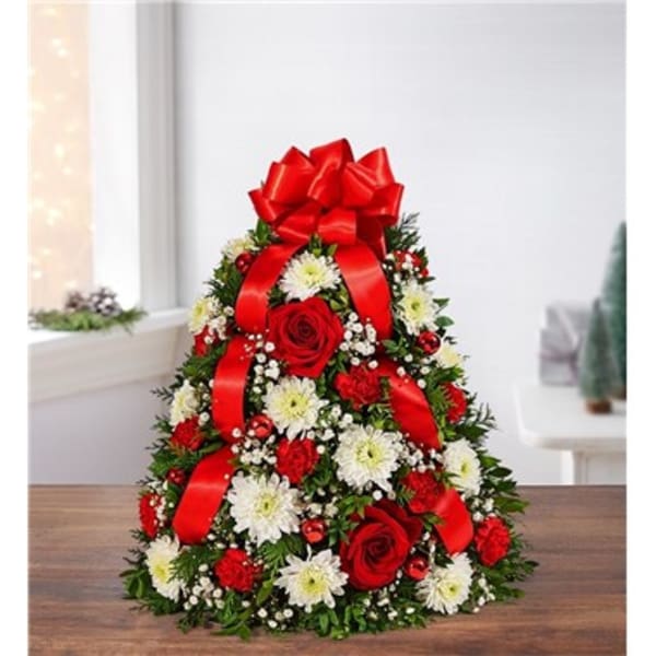 Christmas tree-shaped floral arrangement with red roses, white daisies, and red ribbon