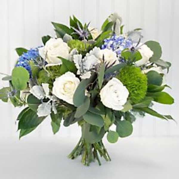 Hand-tied bouquet of white roses, blue hydrangeas, and green pom flowers in a rounded shape
