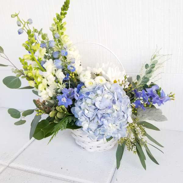 Blue and white floral arrangement in a white basket