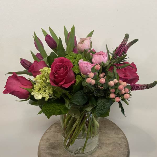 Pink roses and tulips arranged in a glass vase