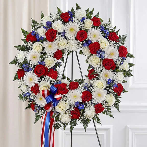 Red, white, and blue floral wreath on a stand with ribbon