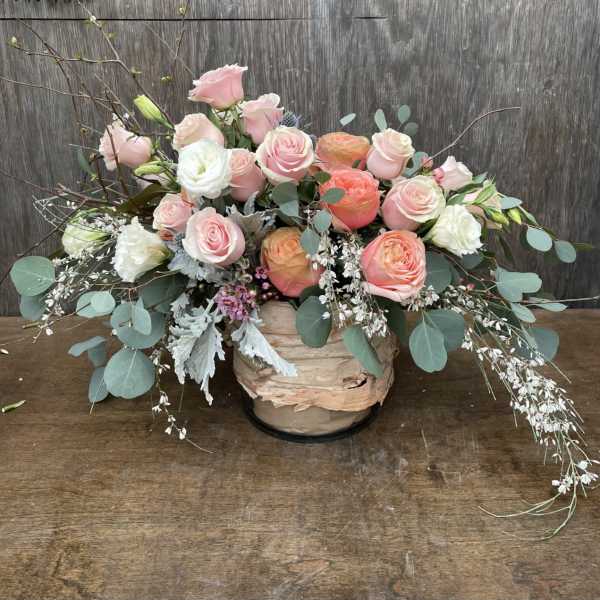 Pink and white roses arranged in a low wooden container