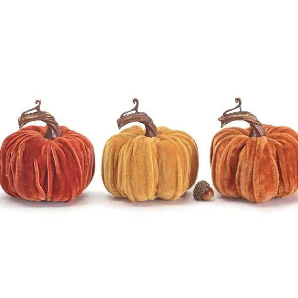 Three velvet pumpkins in orange and gold tones on a white background
