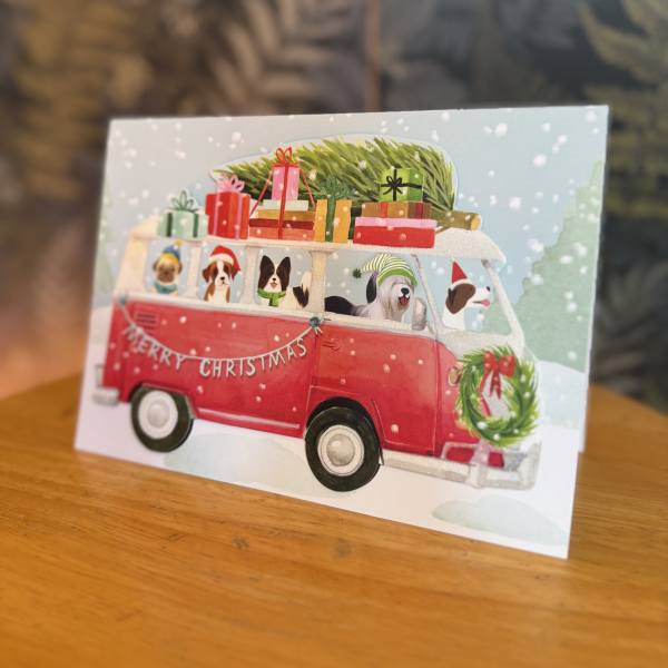 Christmas card with a red van carrying gifts and dogs