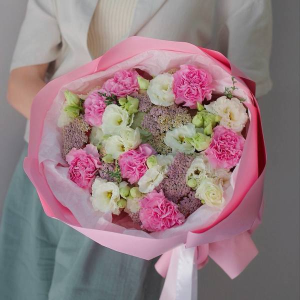 Handheld bouquet of pink and white flowers wrapped in pink paper