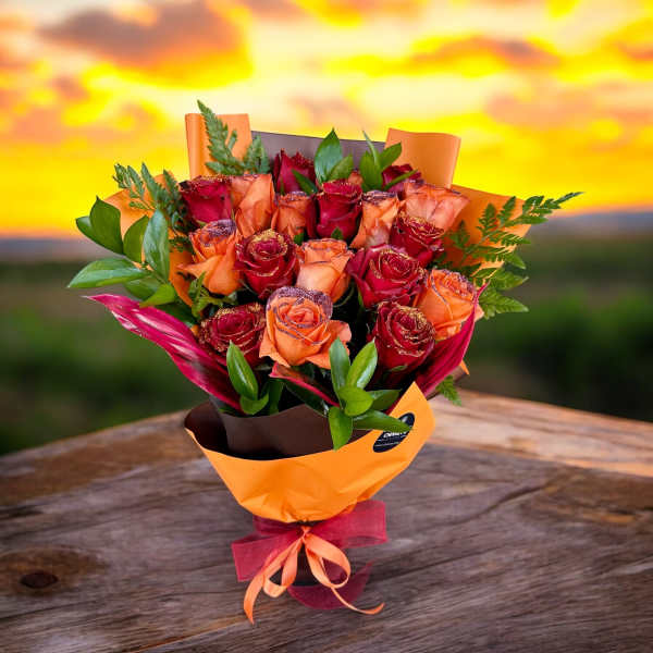 Bouquet of red and orange roses wrapped in orange paper with a ribbon