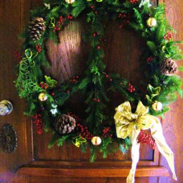 Christmas wreath with pinecones, red berries, and a gold bow on a wooden door