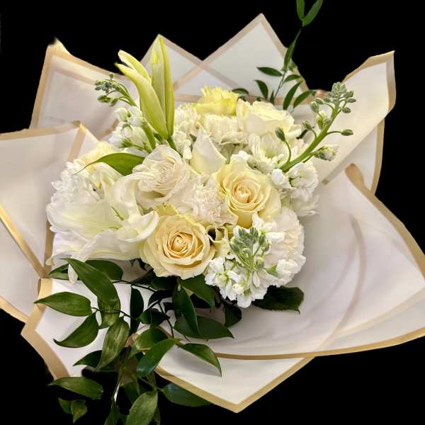 Cream bouquet of roses, lilies, and white blooms wrapped in paper