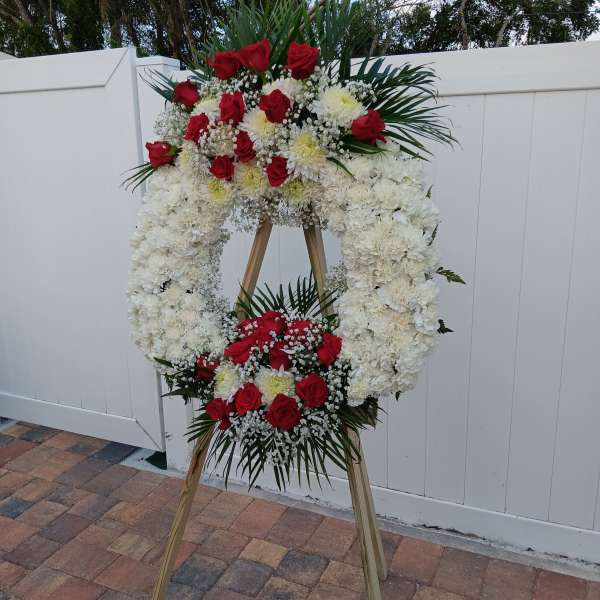 Standing funeral wreath of red roses and white flowers on an easel