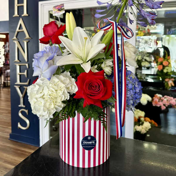 Mixed bouquet with lilies, roses, hydrangeas, and agapanthus in a striped box