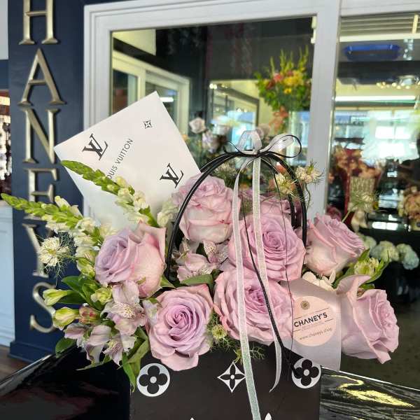 Lavender roses and white flowers in a black gift box with ribbon
