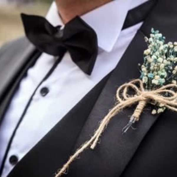 Boutonniere with tiny blue-white flowers tied to a black tuxedo lapel