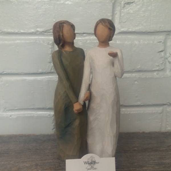 Two carved figurines standing side by side and holding hands