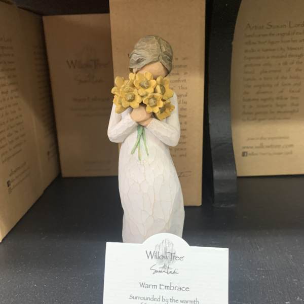 Figurine in a white dress holding a bouquet of yellow flowers