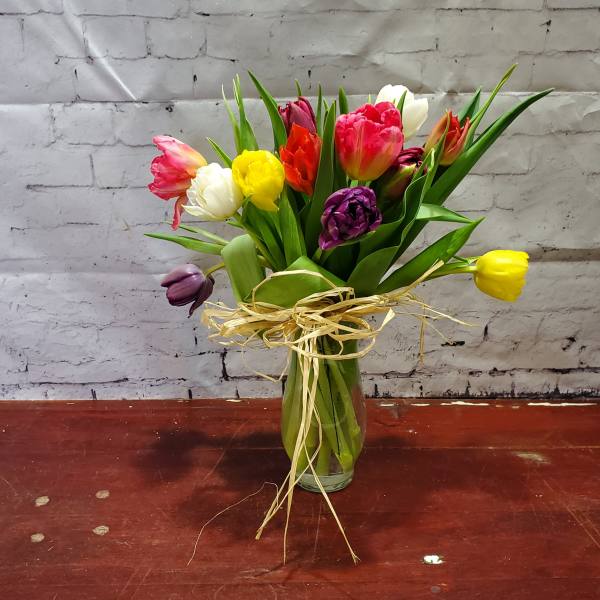 Colorful tulip bouquet in a glass vase with raffia tie