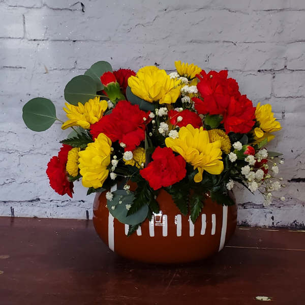 Red and yellow flower arrangement in a brown ceramic vase