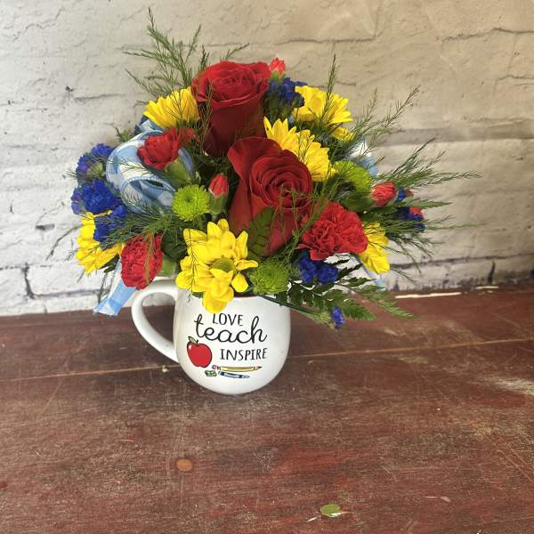 Bouquet of red roses, yellow daisies, and carnations in a mug