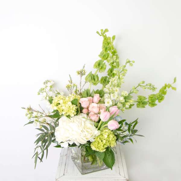 Bouquet of white and pink flowers in a clear square vase
