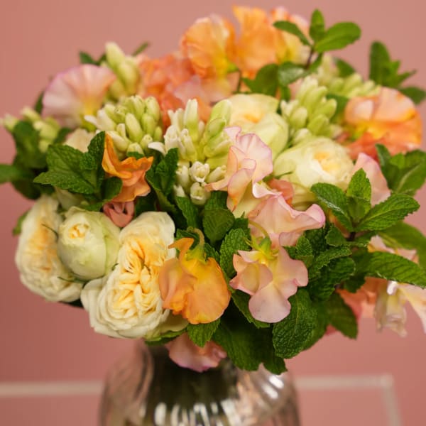 Bouquet of peach and cream flowers in a glass vase