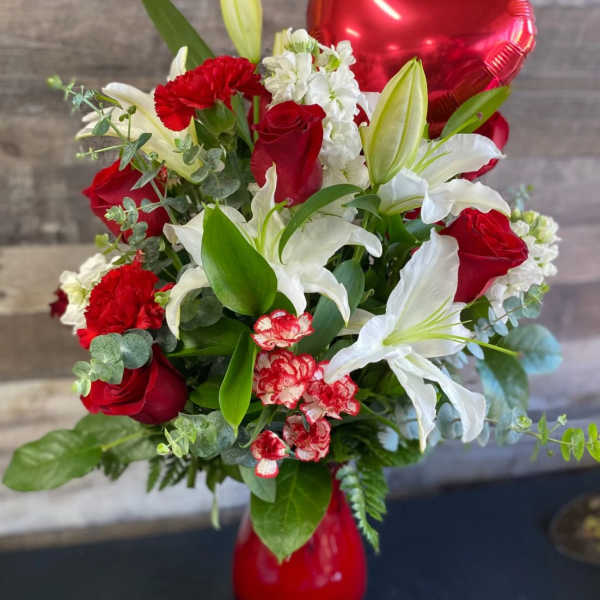 Bouquet of red roses, white lilies, and carnations in a red vase