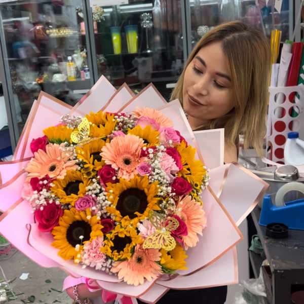 Large bouquet of sunflowers, gerbera daisies, and roses wrapped in pink paper