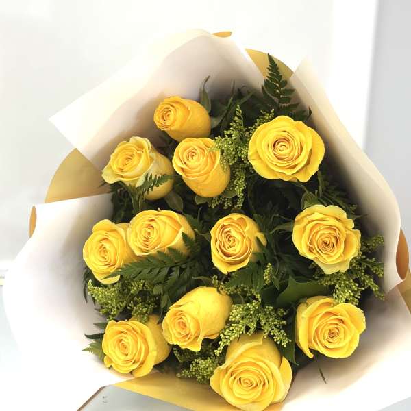 Bouquet of yellow roses wrapped in white and gold paper