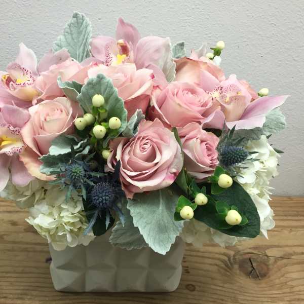 Pink roses and orchids arranged in a white vase