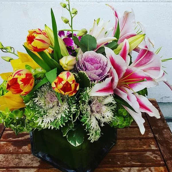 Mixed bouquet with pink lilies, tulips, and purple cabbage in a black box