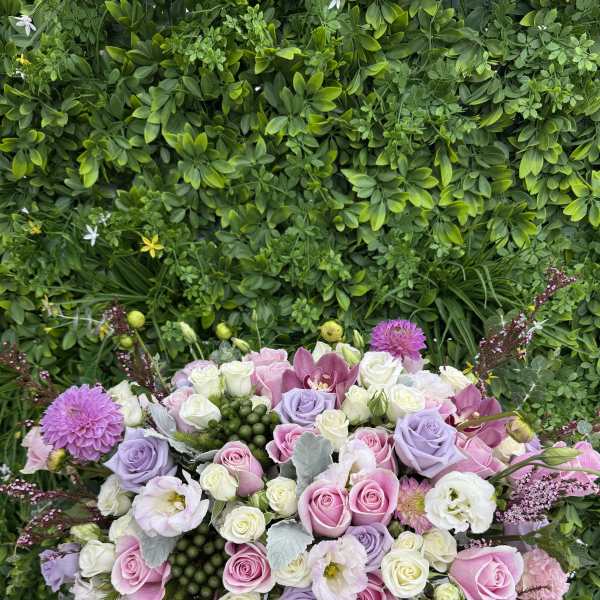 Large pastel bouquet of roses, orchids, and lisianthus in a white container